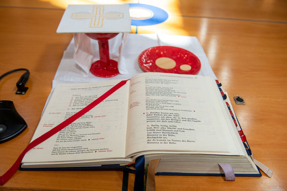 Altar mit Messbuch, Kelch und Hostien auf einem Teller